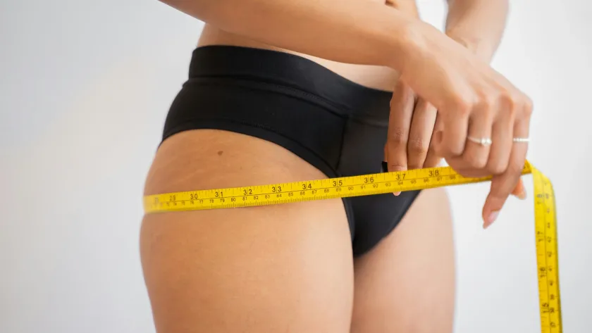 Woman measuring waist showing perimenopause body composition and fat distribution changes