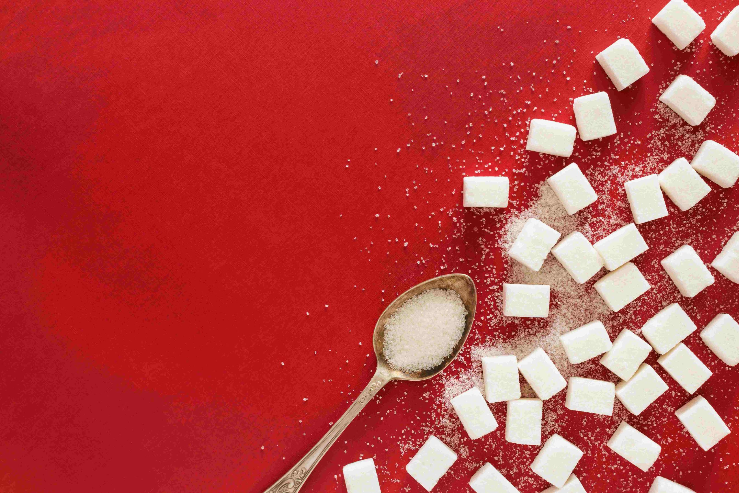 Sugar cubes on red background representing constant sugar cravings and blood sugar